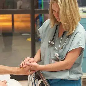 Female nurse holding patient's hand