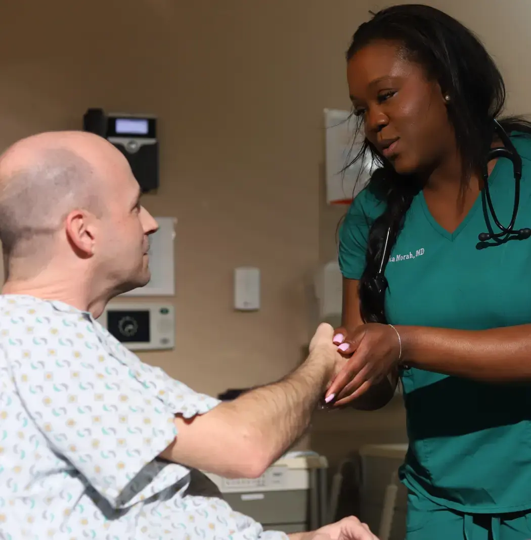 Scholar doctor holding a patients hand while talking